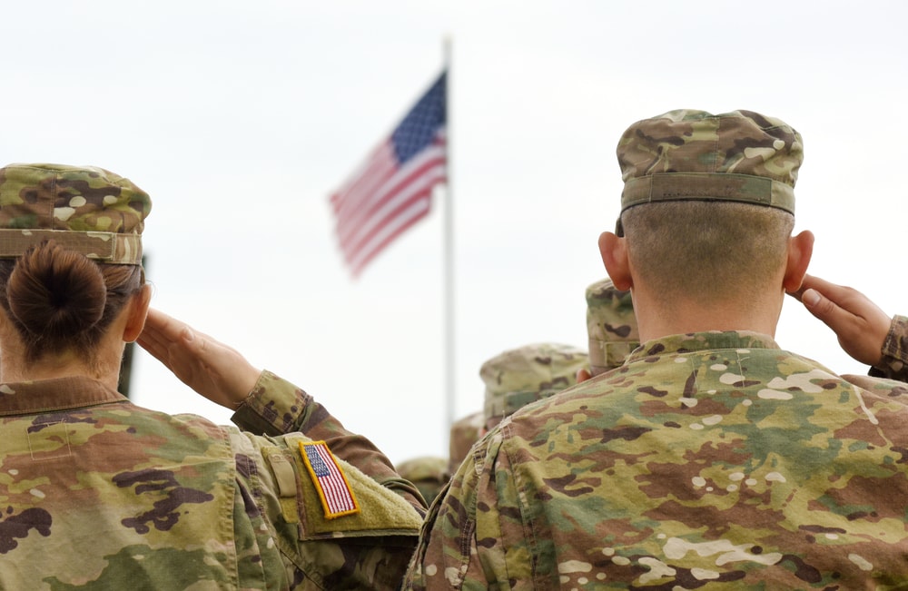 Troops salute the American flag with earplugs in