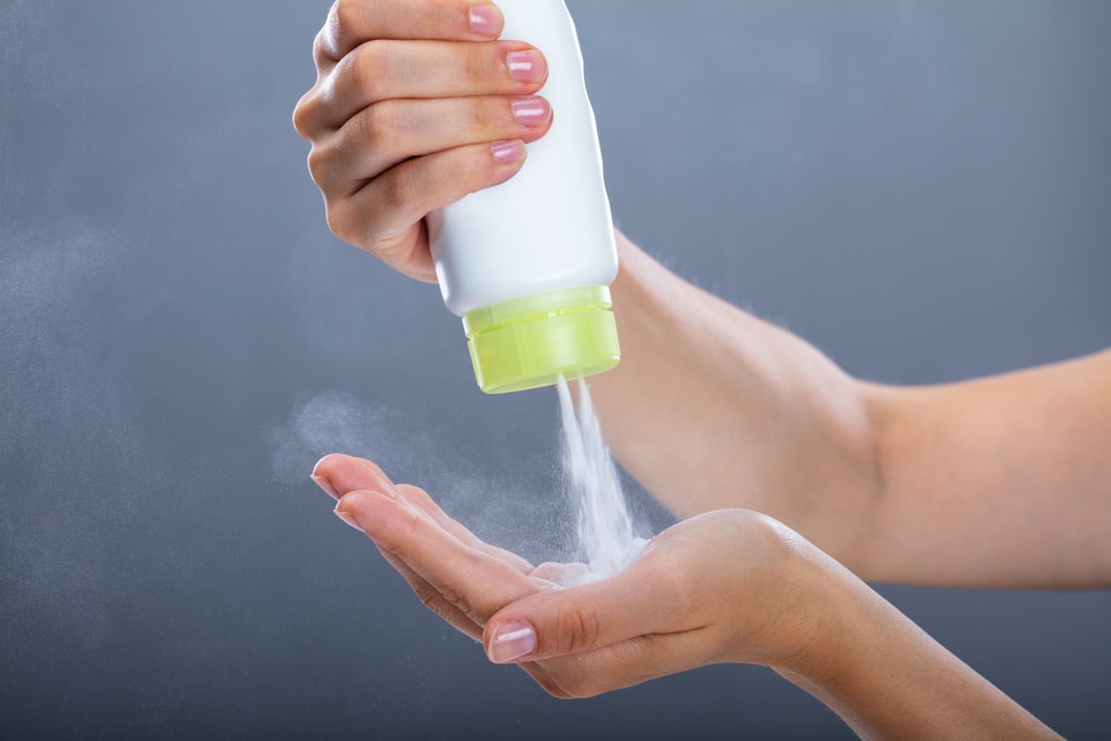 A woman sprays talcum powder into her hand